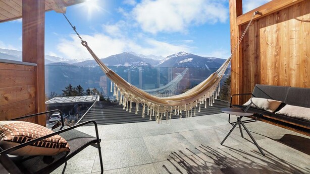 Un hamac dans une pièce en bois avec vue sur la montagne.