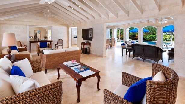 A spacious living area with wicker furniture, a wooden coffee table, and a ceiling fan. - Tropical Oasis with Pool Near Beach - Todmorden (Gibbes Beach)
