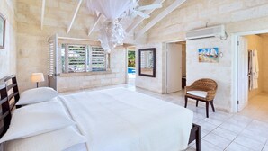 A spacious bedroom with a large bed, a ceiling fan, and a view of the outdoors through a window. - Tropical Oasis with Pool Near Beach - Todmorden (Gibbes Beach)