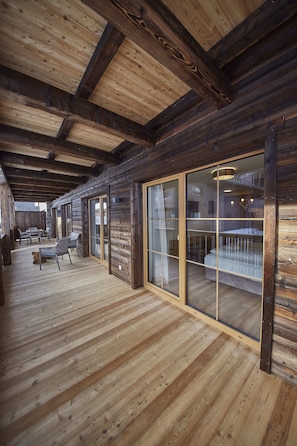 A wooden interior with a high ceiling, a sliding glass door leading to a balcony, and a seating area with chairs. - Residenz Der Wieshofer (Saalbach-Hinterglemm)