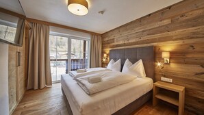 Une chambre avec un grand lit, des murs en bois, une vue à travers une porte coulissante et une table de chevet avec une lampe.