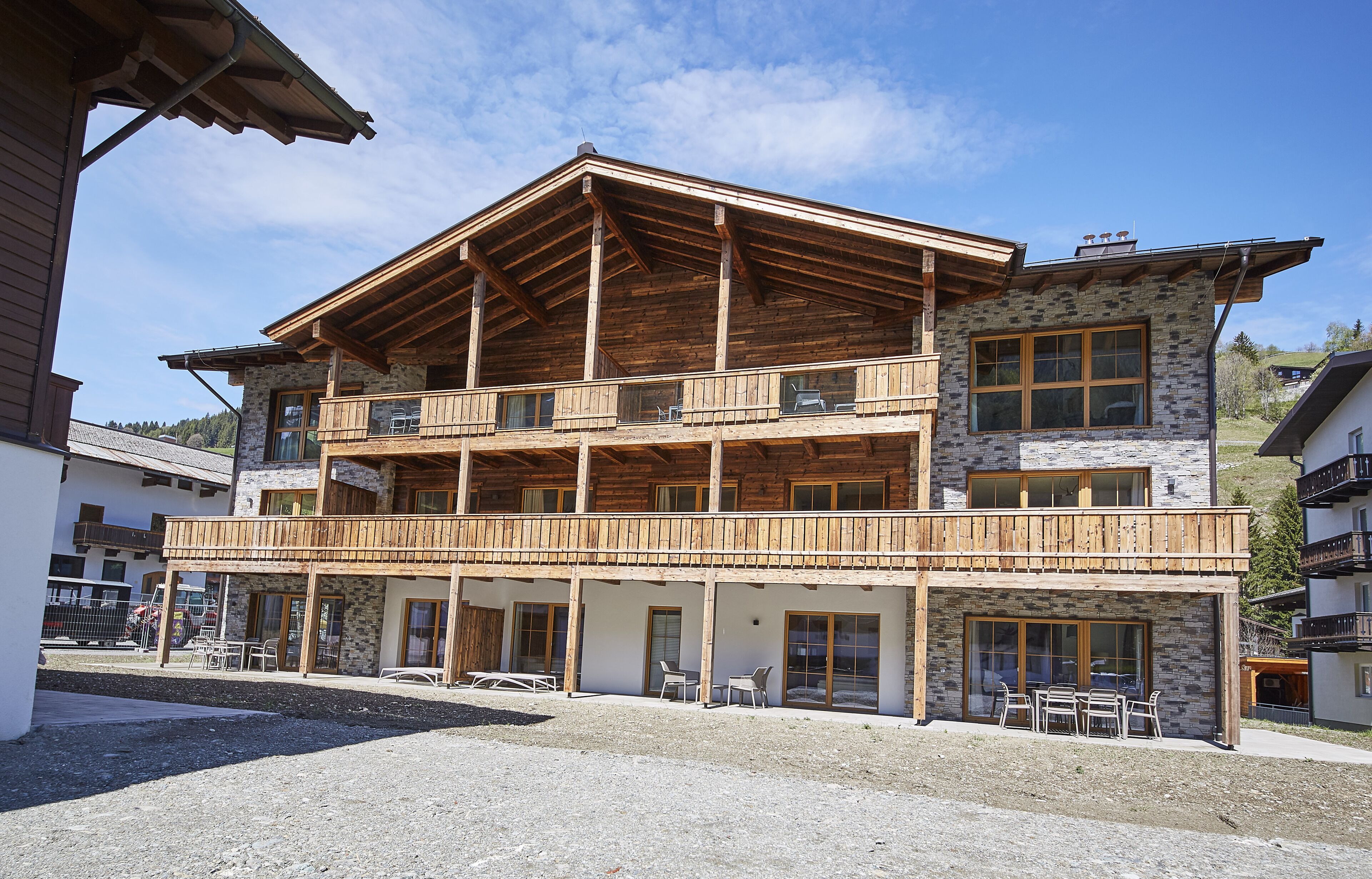 Un bâtiment en bois à deux étages, doté de balcons, de murs en pierre et d’une cour recouverte de gravier.