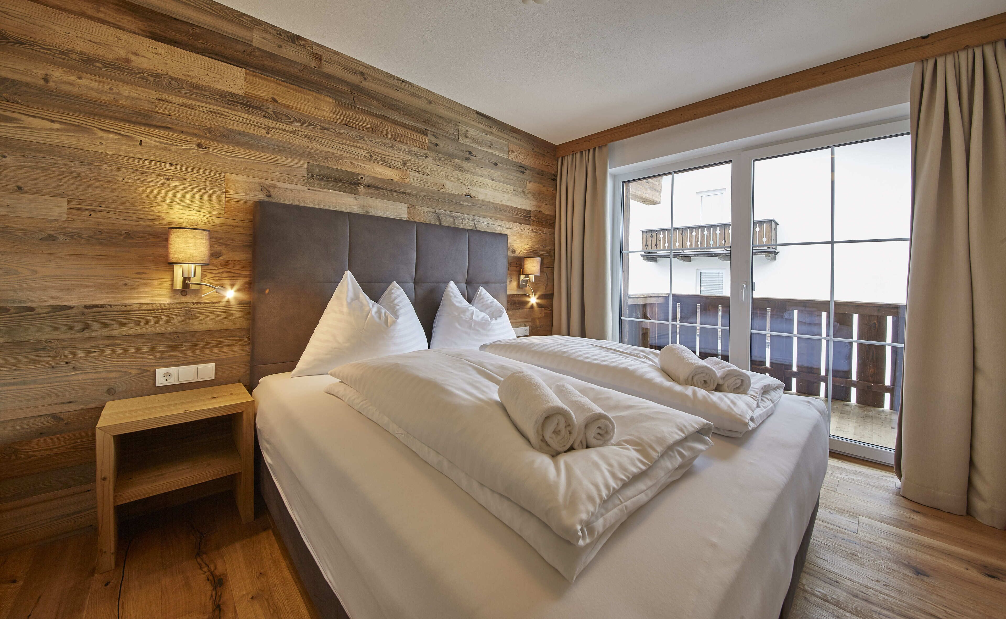 Une chambre d’hôtel avec un grand lit, des murs lambrissés et une vue sur le balcon.