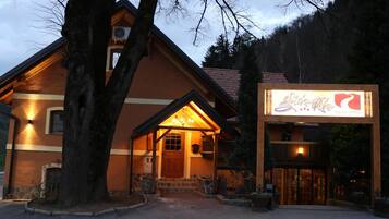 A lodge with a warm exterior, a wooden entrance, and a signboard.