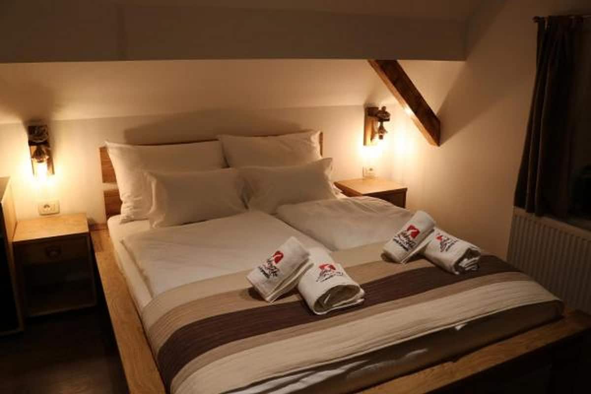 A hotel room with a bed, two bedside tables, and wall-mounted lamps.