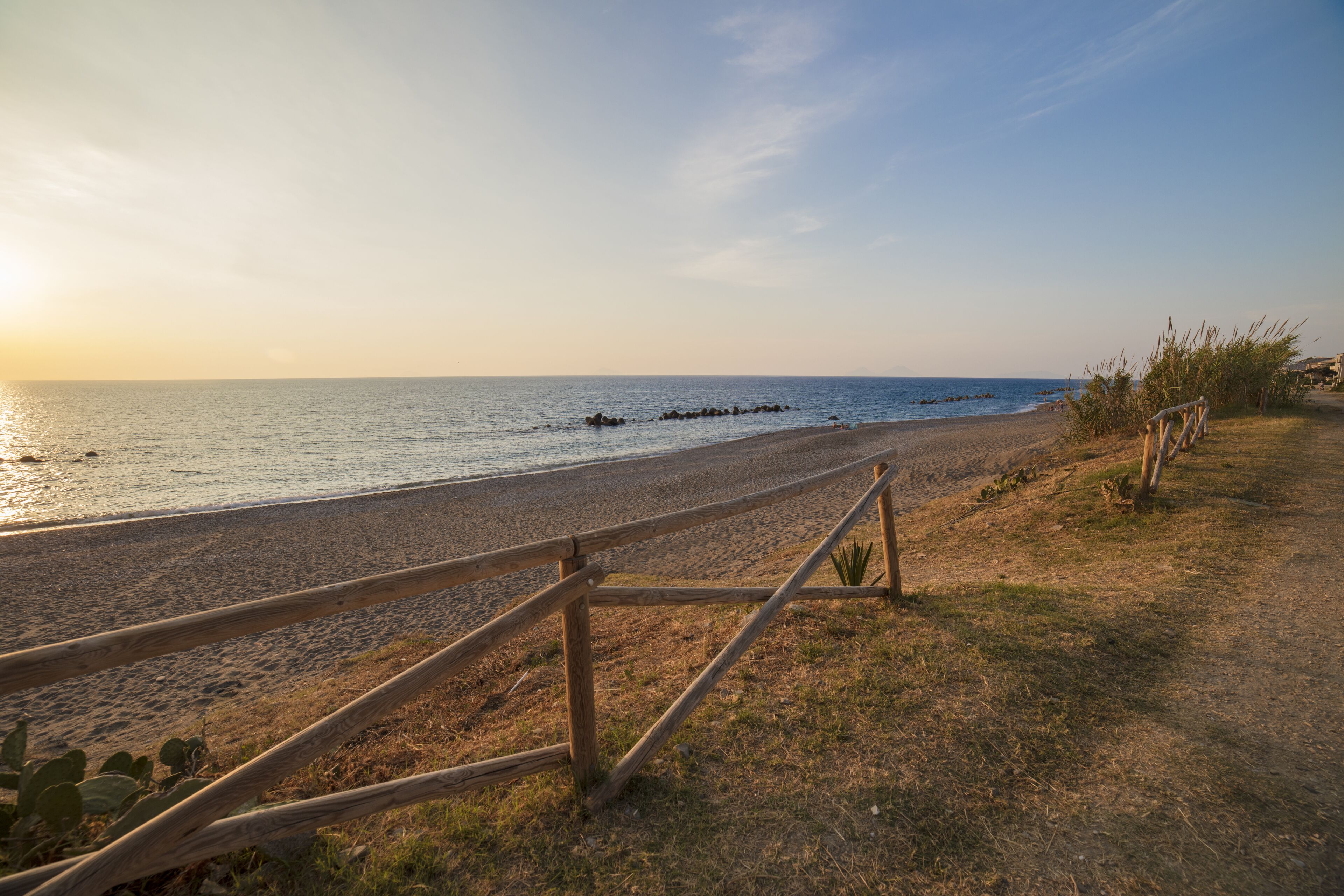 A beach path with wooden railings, leading to the sea.