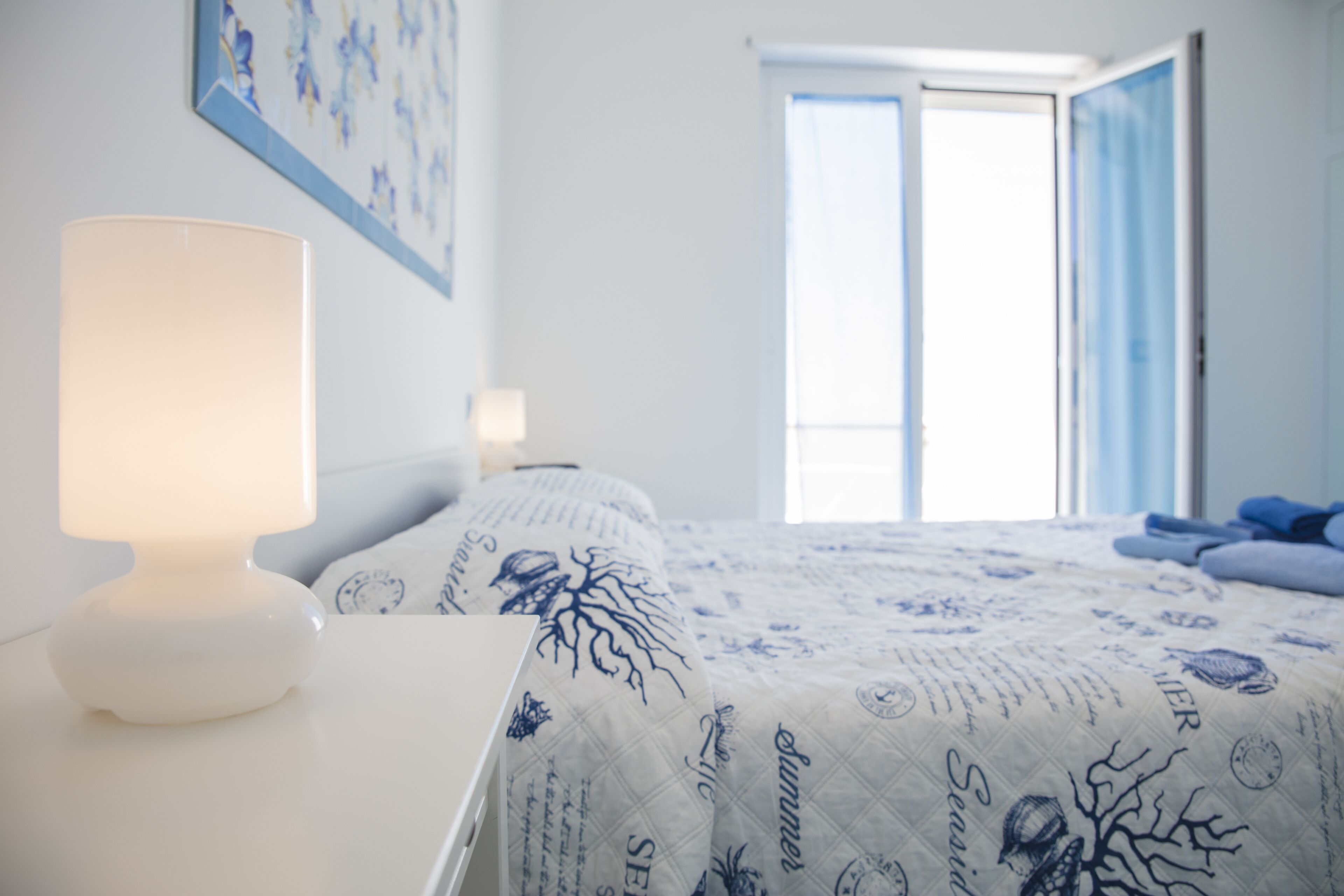 A bedroom with a bed, a bedside lamp, and a window with curtains.