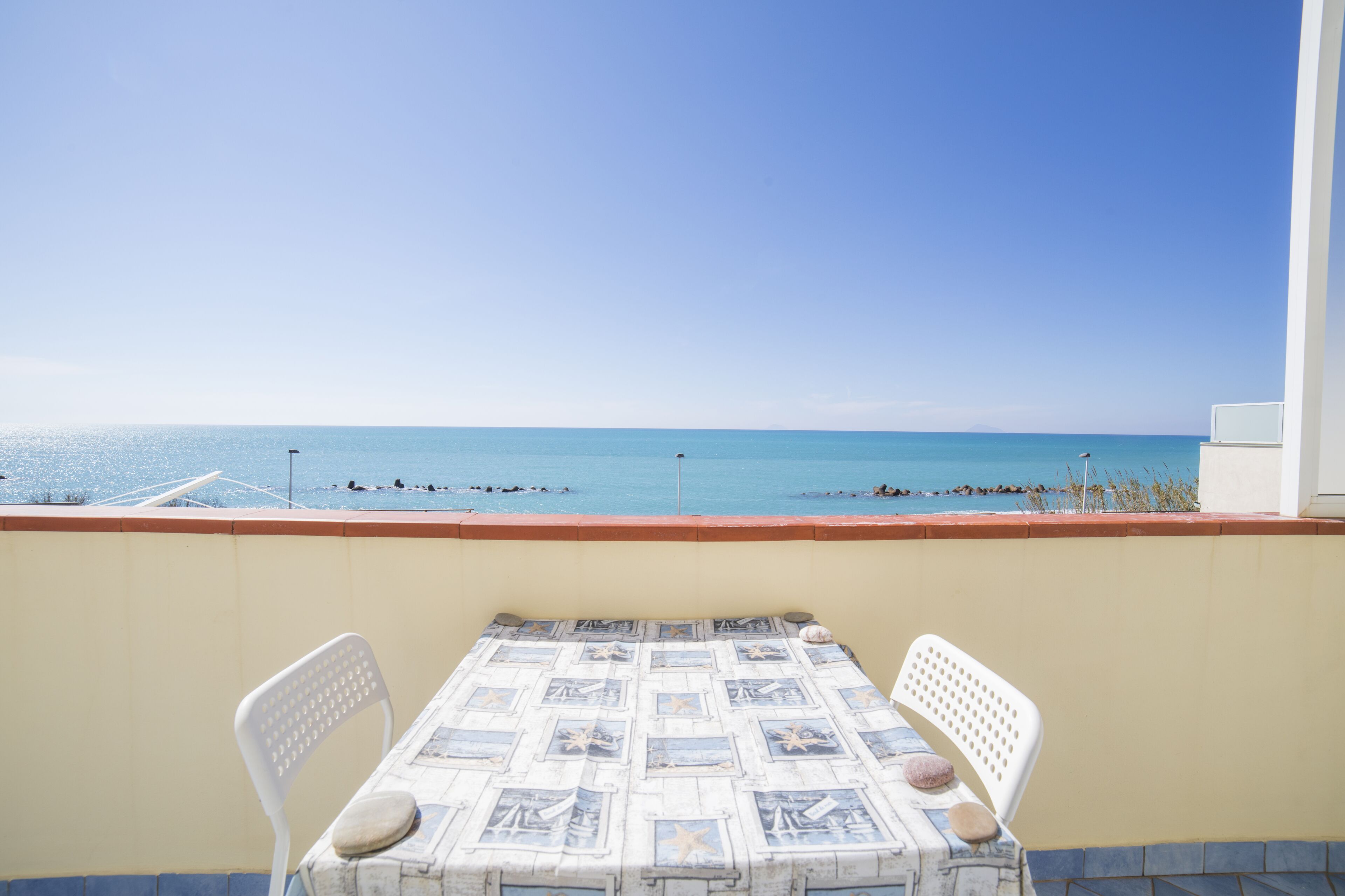 A balcony with a table and chairs overlooking a beach.