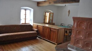 Um quarto com sofá de madeira, cozinha com bancada de madeira e lareira de pedra.