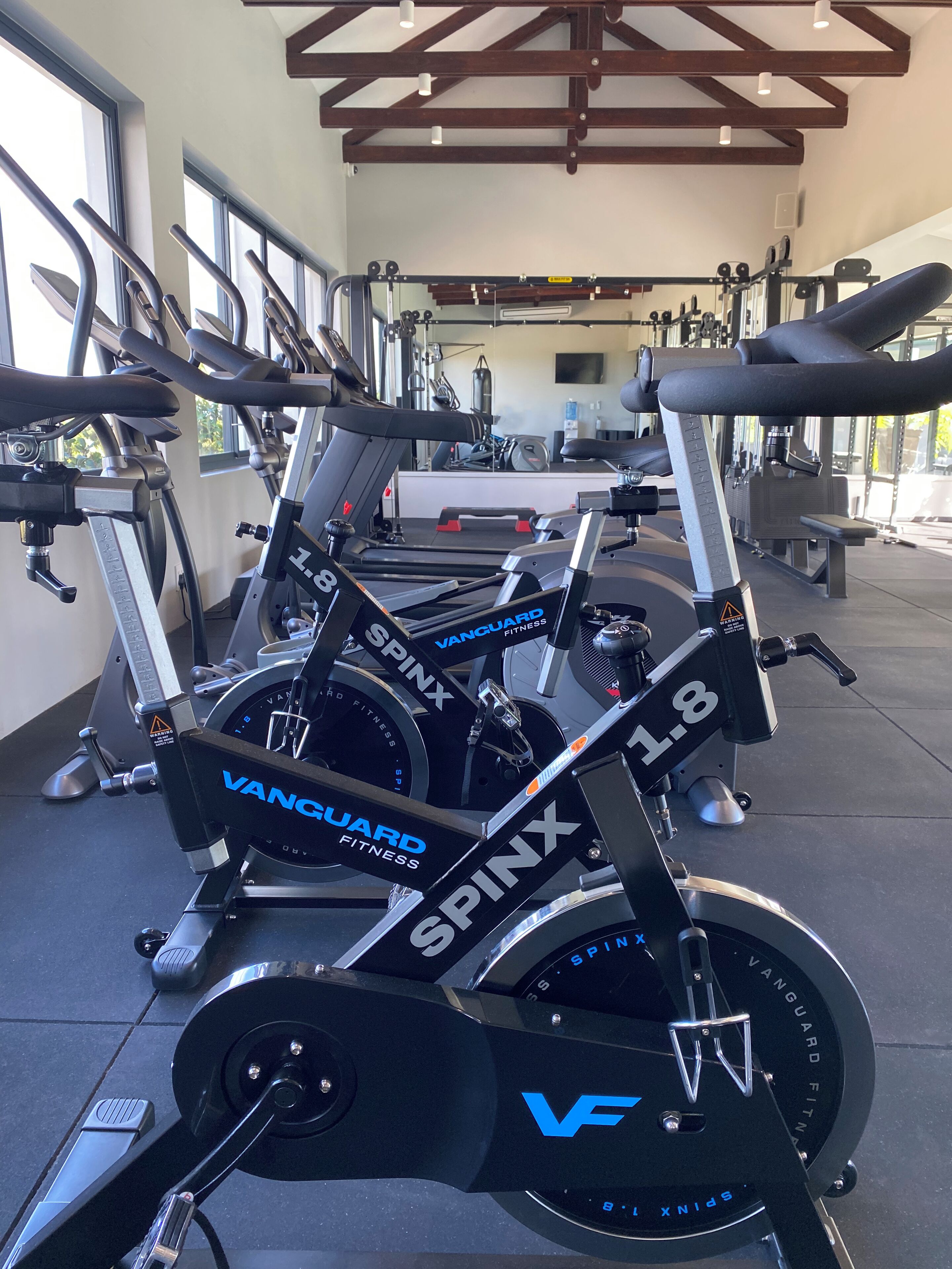 Ett gym med motionscyklar som har namnskyltar med texten ”Vanguard Fitness” och ”SpinX”.