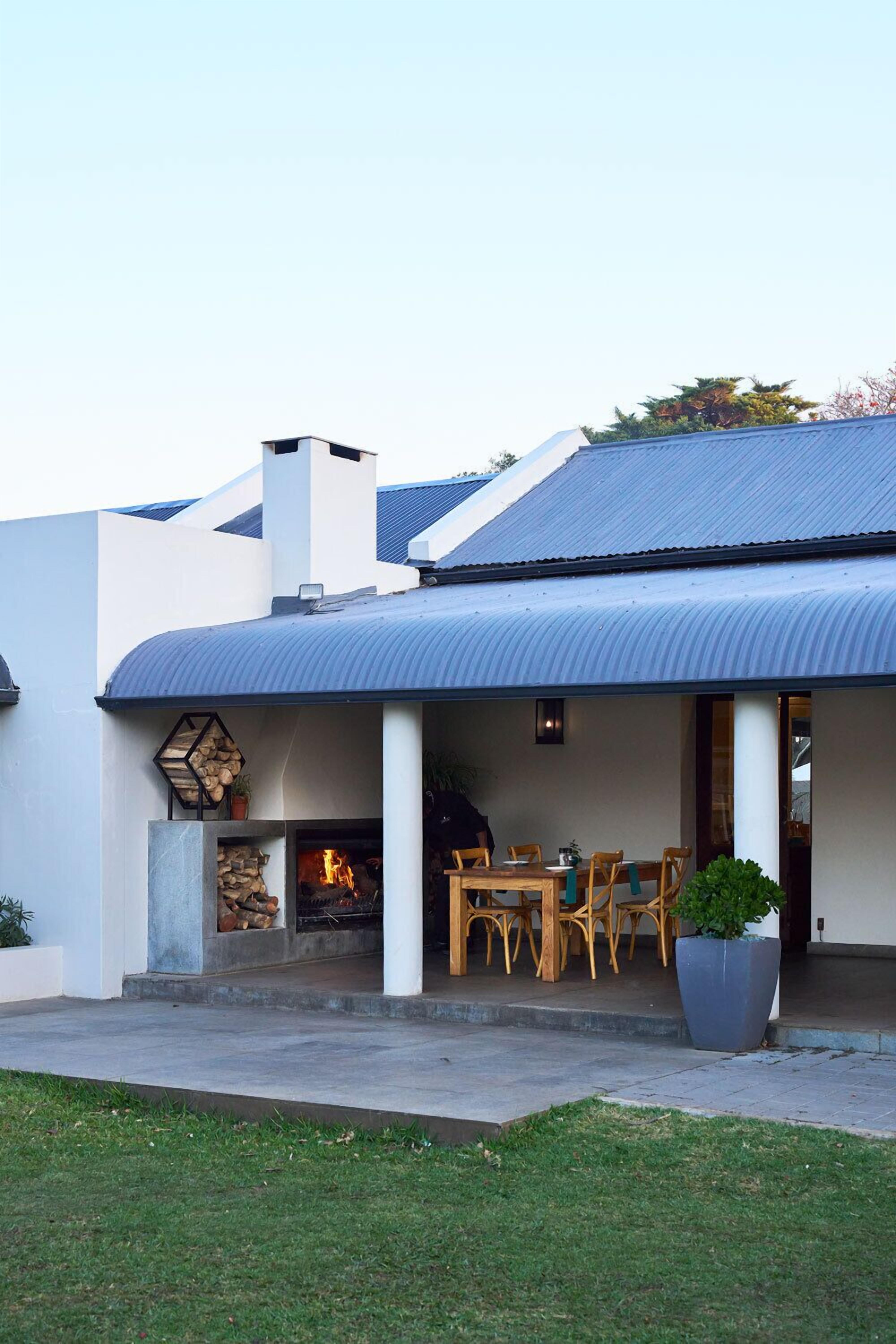 Uma casa moderna com alpendre coberto, lareira e mobiliário de exterior.