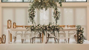 A wedding reception setup with a long table, white chairs, and floral decorations. - Hotel Olivewood (Great Kei)