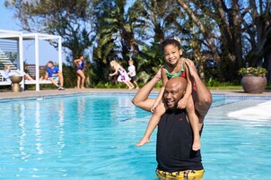 Un hombre lleva a un niño sobre sus hombros cerca de una piscina.