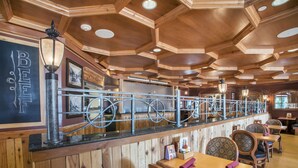 A restaurant with wooden paneling, a bar area with a bicycle-themed railing, and several tables and chairs.