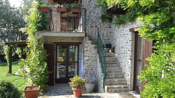 A stone building with a wooden balcony, a staircase, and potted plants. - Villa Malgrè Tout (Bonvicino)