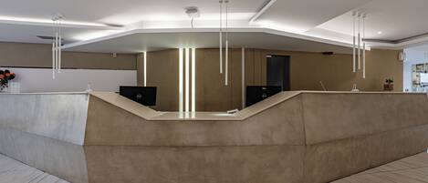 Una moderna reception dalla linea curva, con illuminazione a scomparsa e colori neutri.