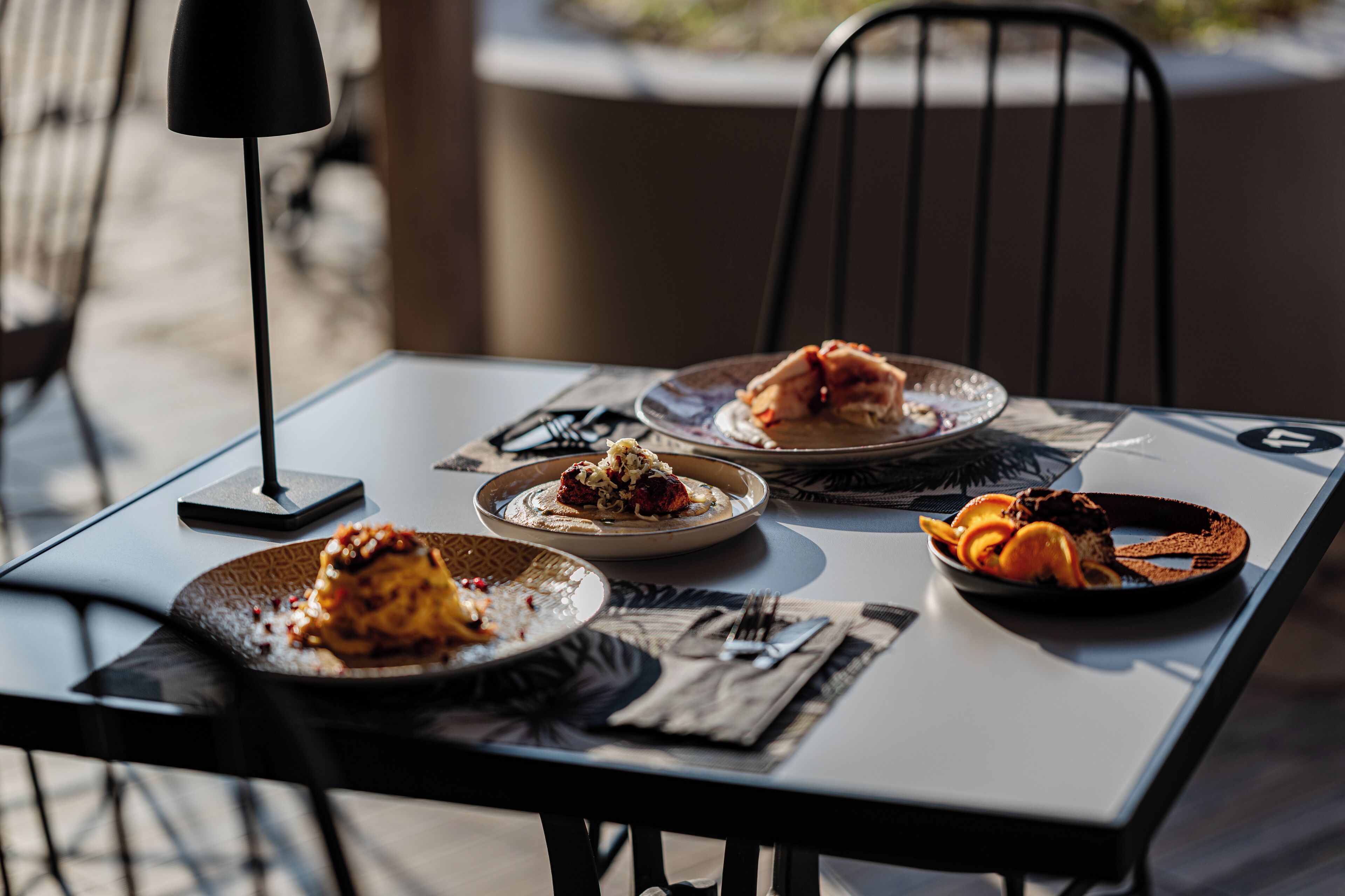 A table with plates of food, cutlery, and a lamp.