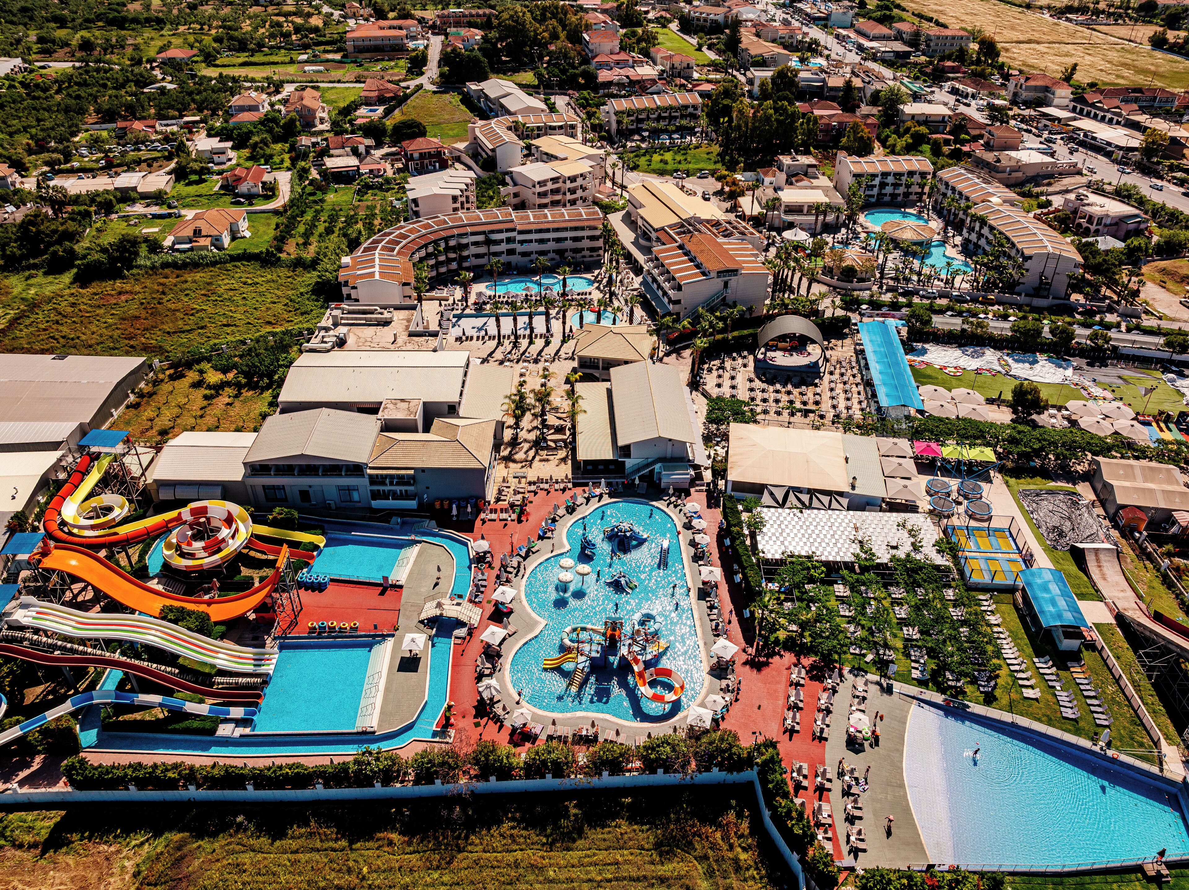 Vista aérea de un complejo turístico con múltiples piscinas, toboganes acuáticos y una gran piscina central con un río lento.