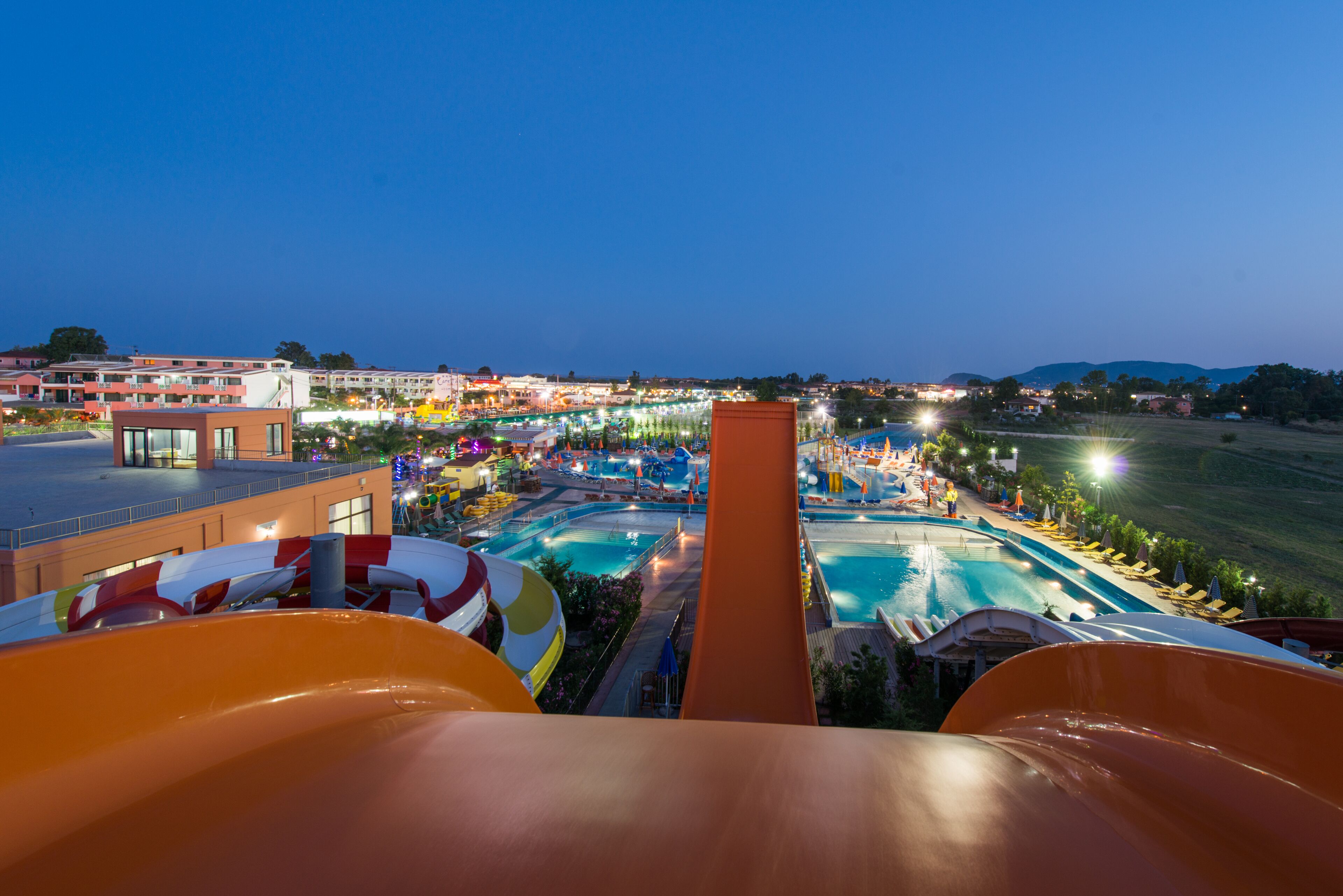 Un parc aquatique doté de nombreux toboggans et de plusieurs piscines, entouré de bâtiments et offrant une vue sur le paysage.