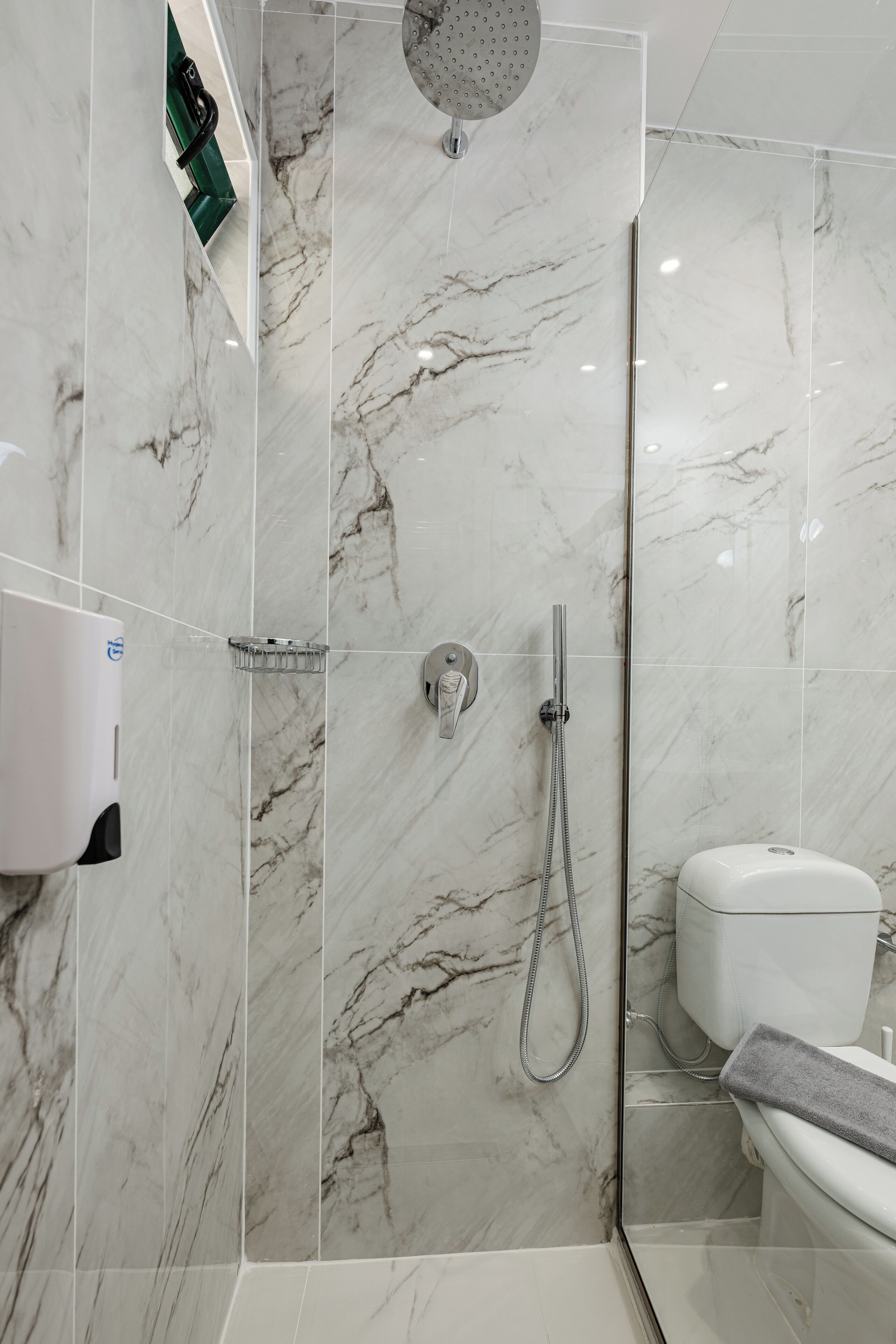 Un bagno moderno con doccia a vetro, un water e un asciugamani ad aria.