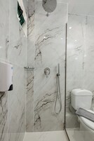 Un bagno moderno con doccia a vetro, un water e un asciugamani ad aria.
