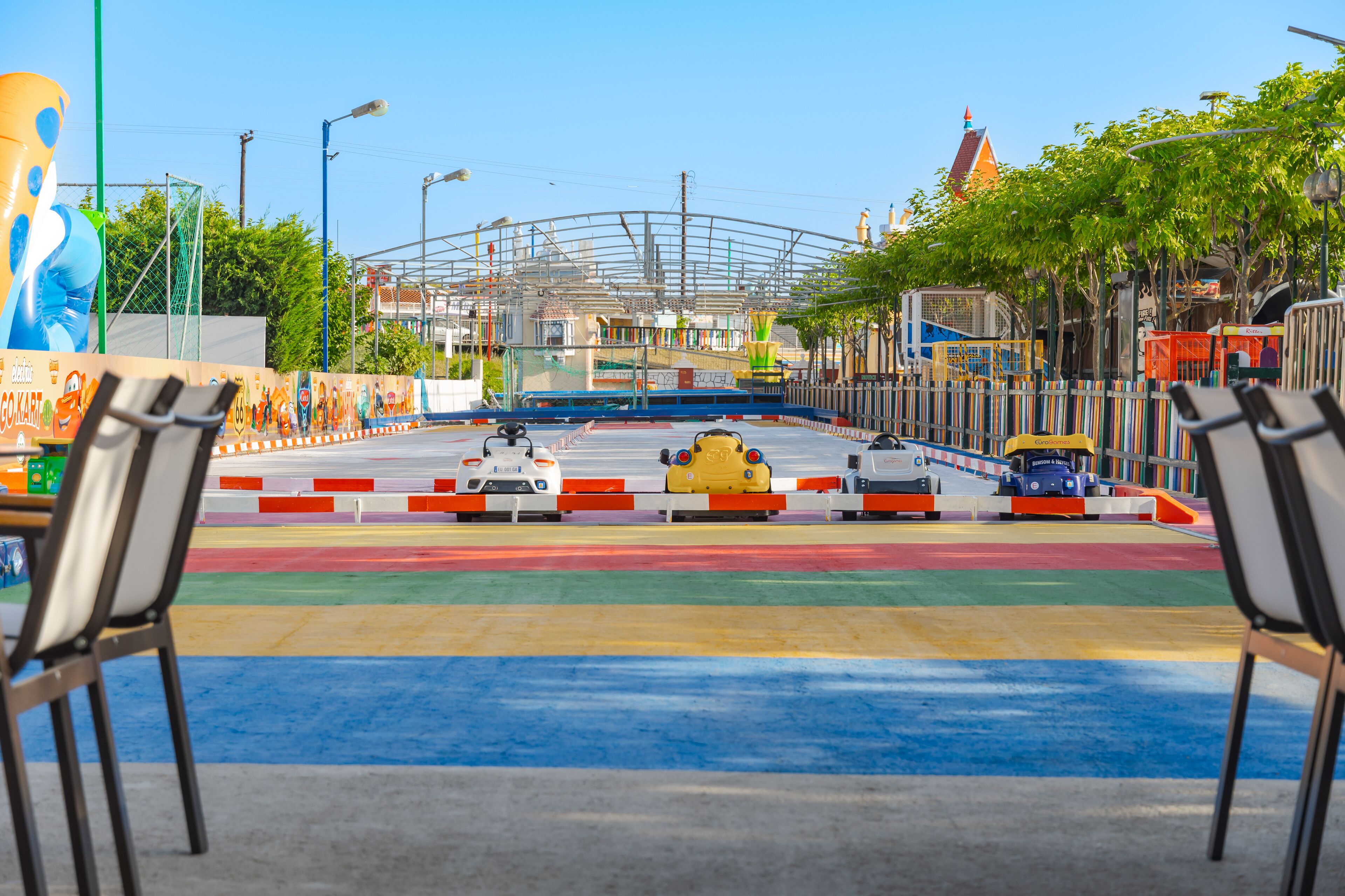 A go-kart track with a clear sky and a large mural on the left.