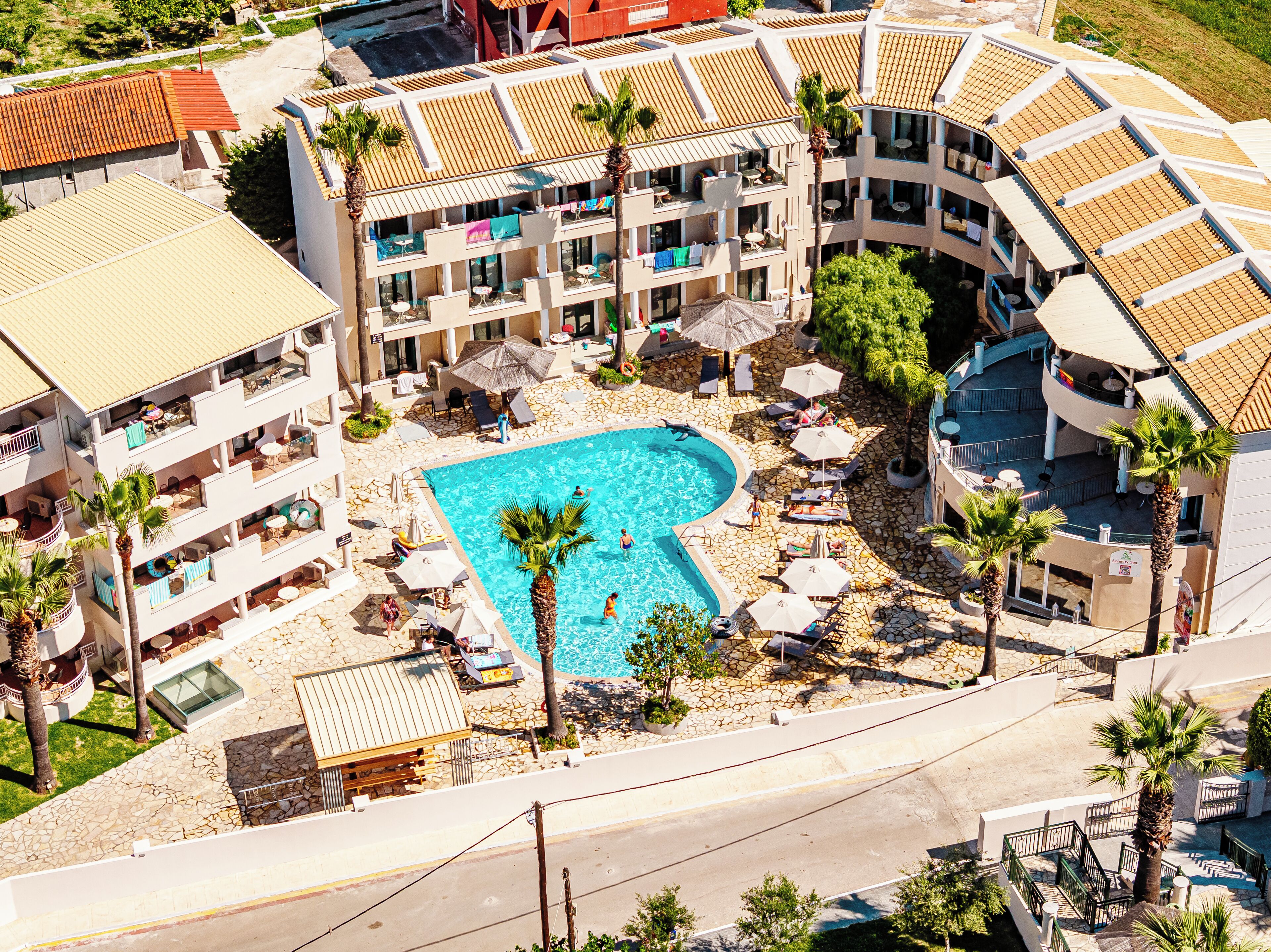 A resort with a central swimming pool, multiple balconies, and outdoor seating areas.