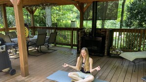 A wooden deck with a yoga mat, chairs, and a grill. - Holyfield Cabin and Bunkhouse (Flag Pond)