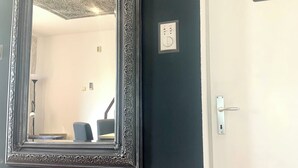 A mirror with an ornate frame on a dark wall, a door with a toilet sign, and a light switch. - Guesthouse Vladimir & Ana (Pancevo)