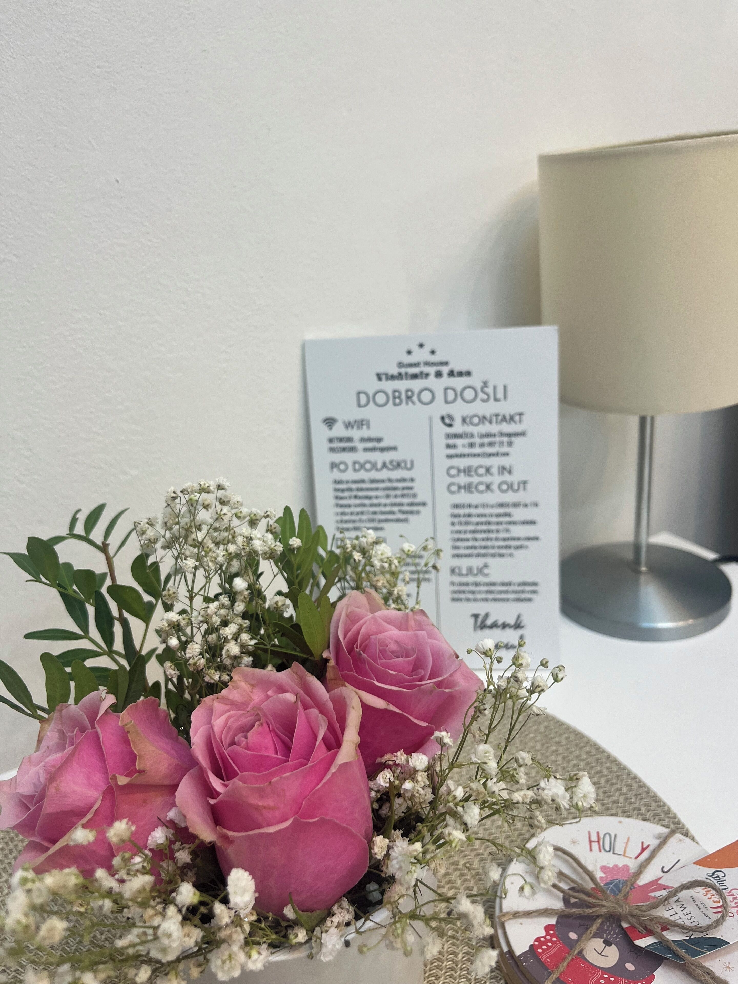 Una mesa con un ramo de rosas rosadas y flores blancas, un menú y un candelabro.
