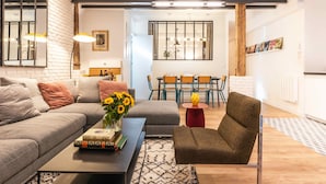 Un salon moderne comprenant un canapé, un fauteuil, une table basse et un coin repas avec une table et des chaises.