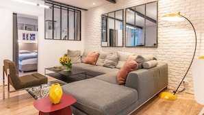 Un salon moderne avec un canapé d’angle, une table basse, une table d’appoint rouge et un vase jaune.