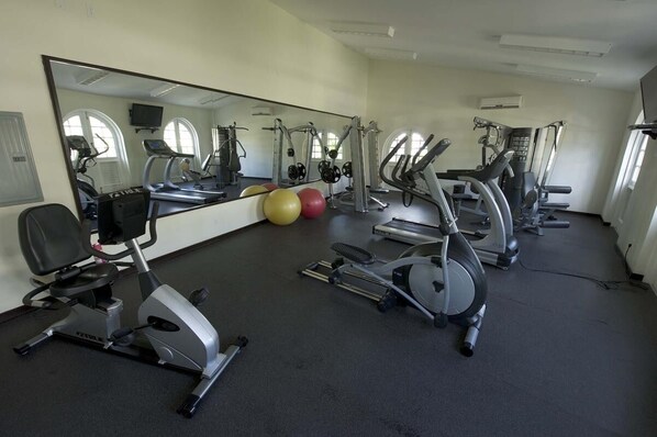 Un gimnasio con bicicletas estáticas, cintas de correr y pelotas de ejercicio.