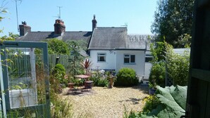 A garden with a gravel path, a small table, and chairs. - 3 bedroom  family friendly and pet friendly cottage in Narberth, Pembrokeshire (Narberth)