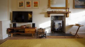 A living room with a television, wooden entertainment unit, fireplace, and artwork on the wall. - 3 bedroom  family friendly and pet friendly cottage in Narberth, Pembrokeshire (Narberth)
