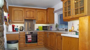 A kitchen with wooden cabinets, a stainless steel oven, a microwave, and a sink. - 3 bedroom  family friendly and pet friendly cottage in Narberth, Pembrokeshire (Narberth)