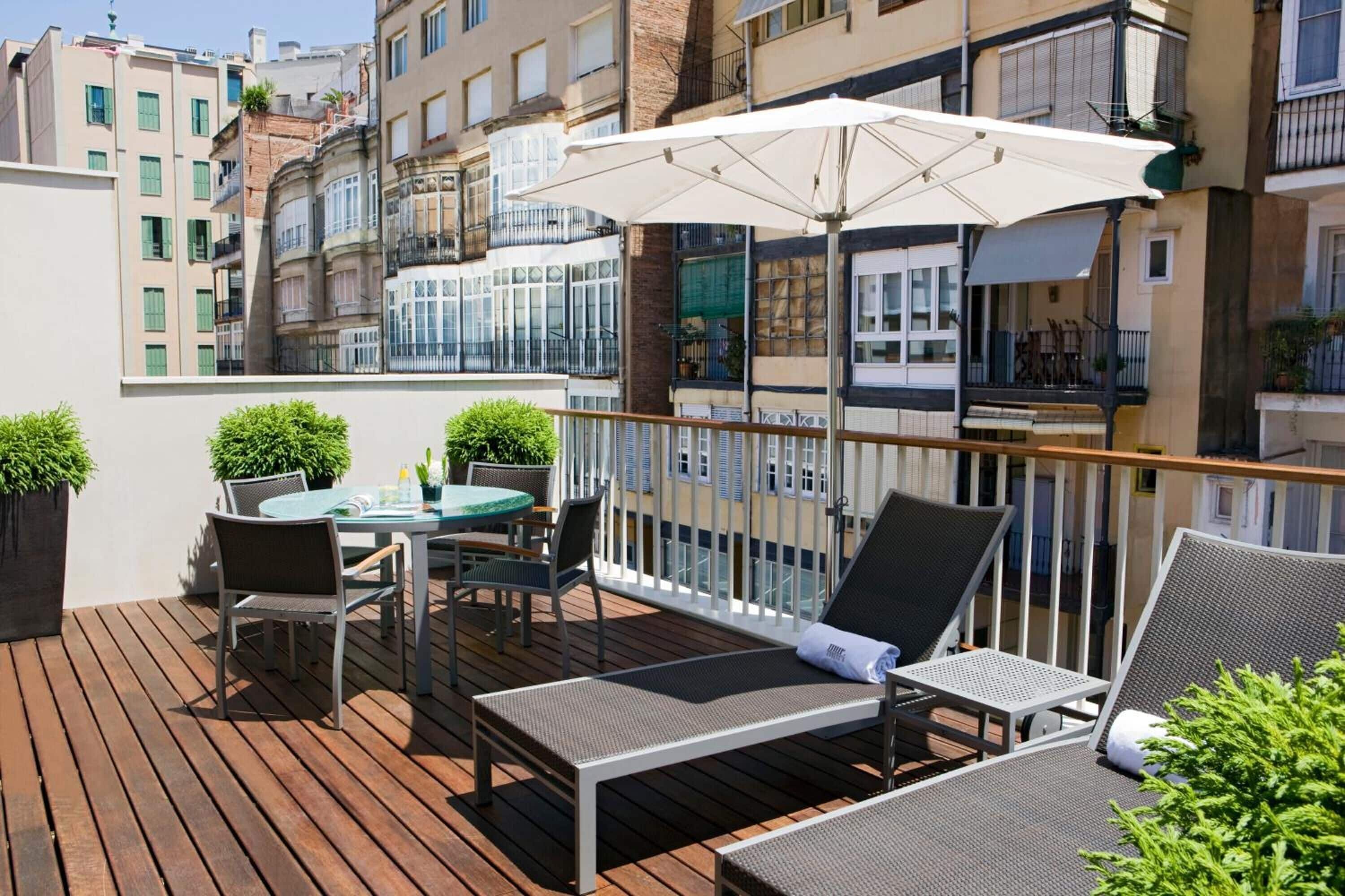A wooden deck with outdoor furniture, including a table and chairs, and a lounge area with a large umbrella.