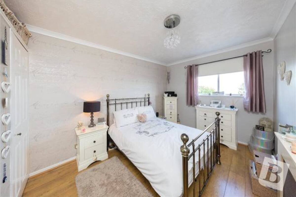 A bedroom with a bed, bedside tables, a dresser, a window with curtains, and a door with heart-shaped decorations.