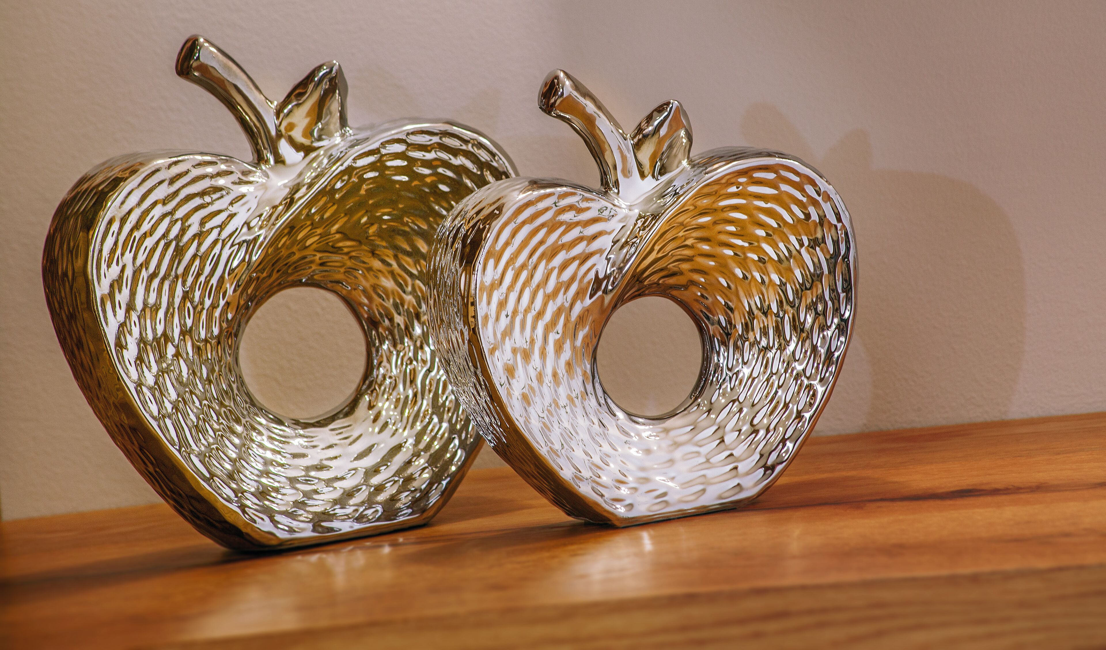 Two glass sculptures resembling apples with textured surfaces and circular openings.