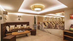 A modern hotel room with a large bed, a sofa, a coffee table, and a mirror. - Hotel Chasa Sulai (Ischgl)