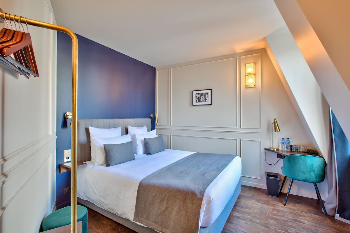A neatly arranged hotel room with a large bed, a desk, and a chair.