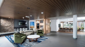A spacious lobby with a stone wall, a fireplace, and a modern seating area with a round table and two armchairs.