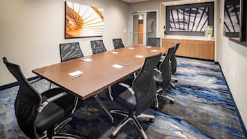 Une salle de conférence avec une longue table, six chaises et une grande fenêtre.