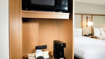 Quarto de hotel com micro-ondas, cafeteira e frigorífico na bancada.