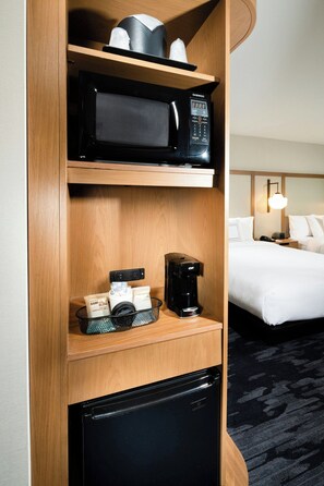 Ein Hotelzimmer mit einer Mikrowelle, einer Kaffeemaschine und einem Kühlschrank auf der Arbeitsfläche.