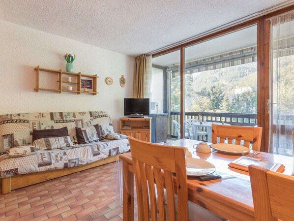 Ein gemütliches Wohnzimmer mit Sofa, Fernseher und Esstisch.