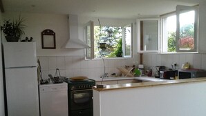 A kitchen with white cabinets, a stove, a sink, and a window with a view of greenery.