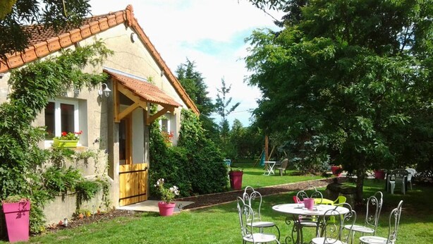 A house with a wooden door and a small patio with metal chairs and a table.