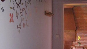Une pièce avec un mur en briques, une chaise en bois et une petite table sur laquelle se trouve un vase.