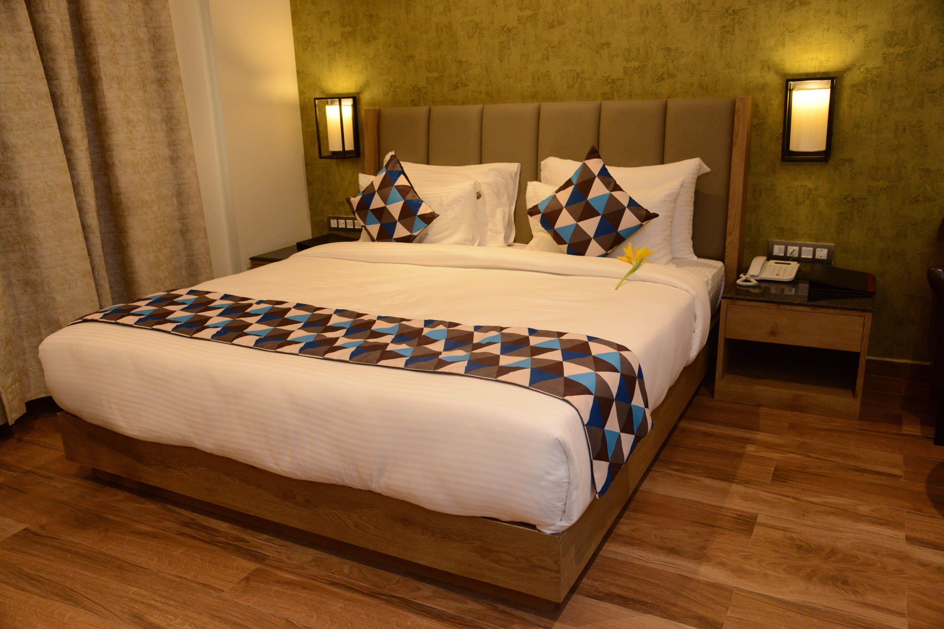 Une chambre d’hôtel avec un grand lit, un plancher en bois et deux tables de chevet avec des lampes.
